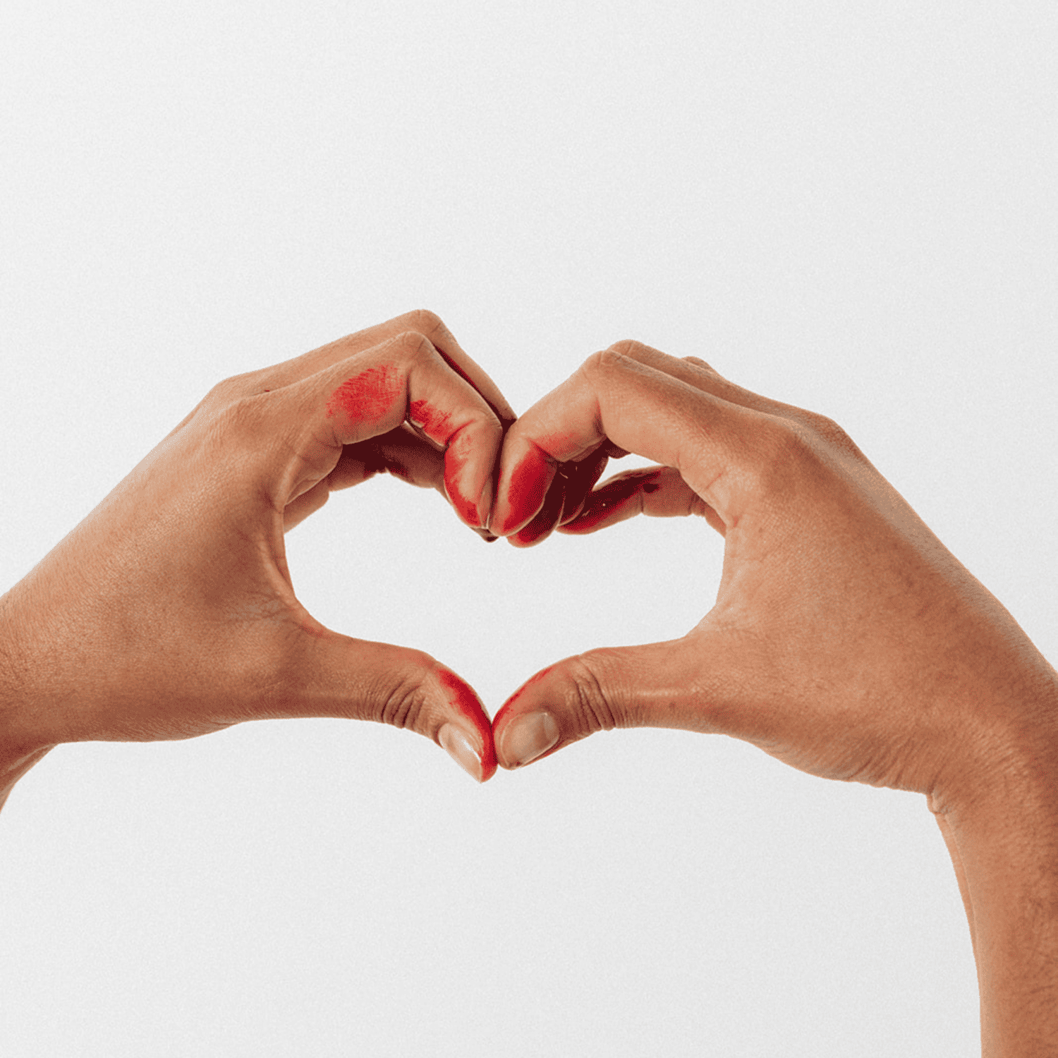 Deux mains formant un cœur avec des traces de rouge évoquant le sang menstruel, symbolisant l'acceptation, l'amour propre et la normalisation des règles abondantes.