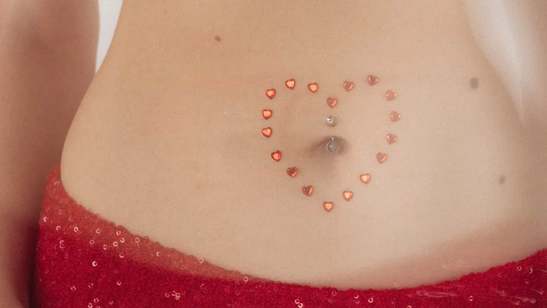 Zoom sur un ventre avec des cœurs rouges formant un cœur autour du nombril, symbolisant la communauté bienveillante Nunina pour les femmes menstruées.